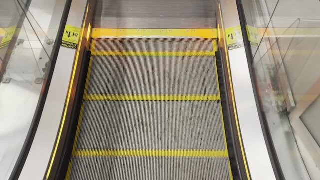 Escalator steps descending with caution signs and metal surface details visible