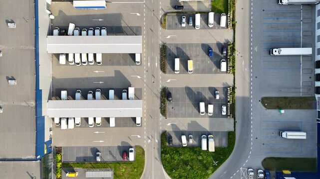 Aerial view of logistics warehouse with trucks parked in designated areas, showcasing organized loading zones and efficient space utilization in a commercial transport facility