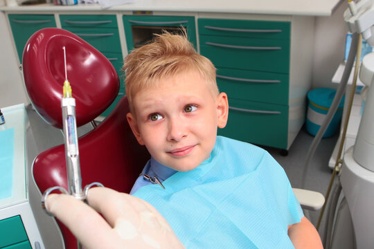 Little boy is very afraid of injection. Childish fear. Syringe is in doctor's hands. Dentist's appointment. Treatment of baby teeth. Negative emotions