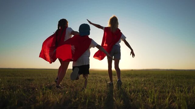 Children in superhero costumes having fun. family enjoys playful moments as Children with red capes run through field. children embrace superhero fun. Family bonding through outdoor superhero play.