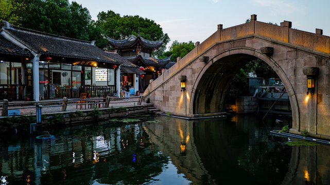 Evening scenery of stone arch bridge in Zhouzhuang Ancient Town, Jiangnan water town, traditional Chinese buildings with warm lantern lights and river water reflection