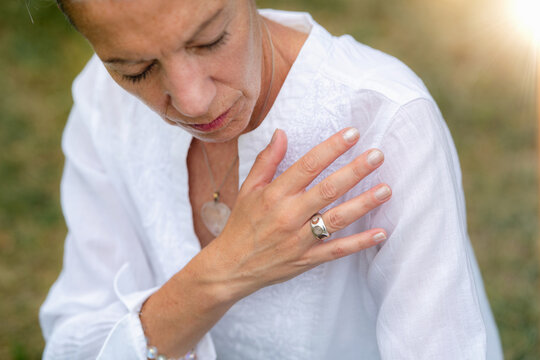 Woman performing a mindful shoulder healing technique using gentle touch to encourage relaxation, body awareness, natural energy flow, and holistic wellness.