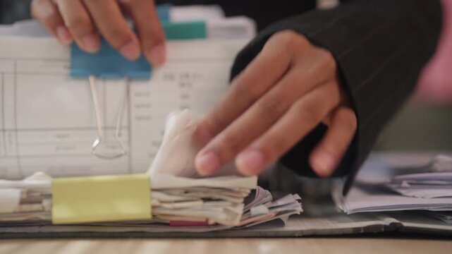 Close-Up of Office Worker Organizing Paper Files with Color-Coded Tabs for Document Management