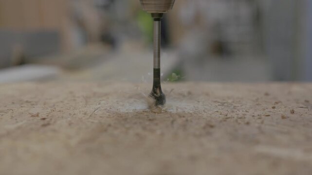 Close-up of worker drilling a hole in an oriented strand board (OSB) panel with a cordless drill during home construction