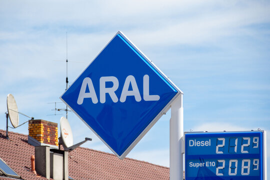 ARAL gas station blue diamond sign displays fuel prices Diesel Super E10 euro litre residential rooftops satellite dishes background clear sky Germany energy market costs, Feuerbach, GERMANY, 2026