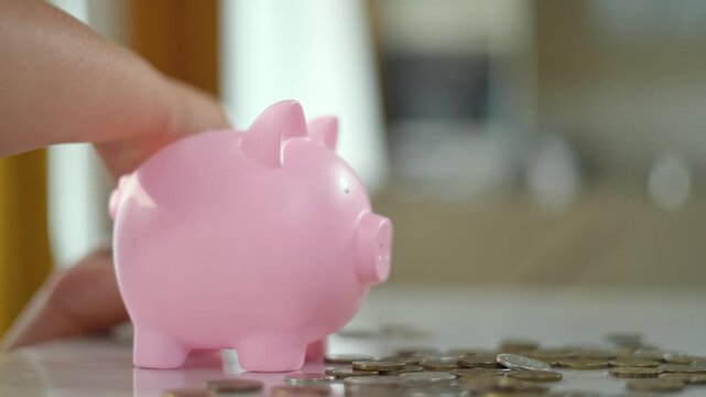 Child saving money at home. Child placing coins into piggy bank. finance education. Child learning to manage money with piggy bank. Financial habits developed at home. Teaching finance skills children