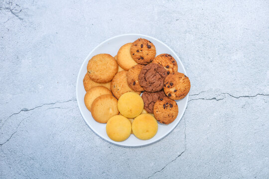 Assorted cookies and biscuits on a plate on the table. Collection of sweet baked snacks including chocolate cookies, butter biscuits, crackers and sandwich cookies on a plate