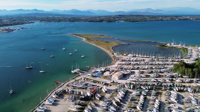 A beautiful drone horizontal wide shot of Cleopatra Marina shipyard in Aktio, displaying rows of yachts and boats in dry dock storage and sailing, with Preveza city and sea in the background.