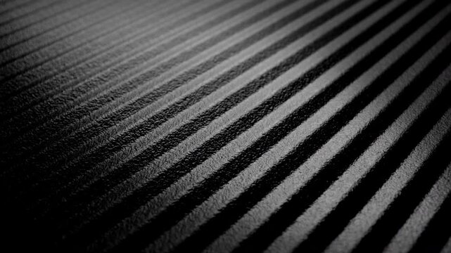 Striped ribbed texture slow rotation. Close-up of black and gray parallel ridges with textured surface. Smooth continuous rotation reveals shifting light and shadow across the linear pattern.