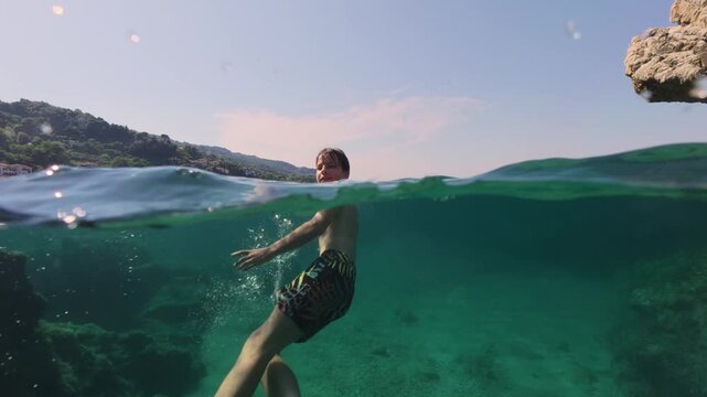Boy swimming split shot over under half underwater
