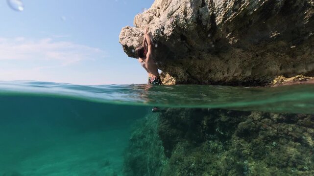 Boy climbing rock split shot over under half underwater