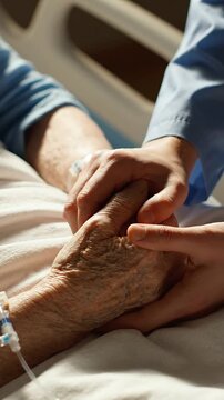 A Tender Moment of Care: An Elderly Hand Being Held Comfortingly by a Caregiver in a Hospital Setting, Symbolizing Compassion and Human Connection