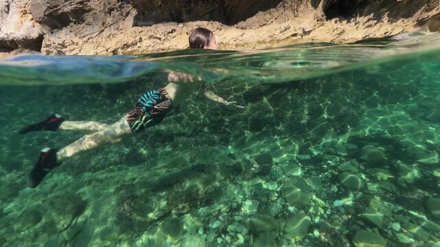 Boy swimming split shot over under half underwater