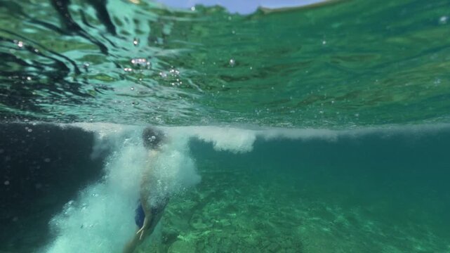 Split level view of a boy jumping into the sea water with splash