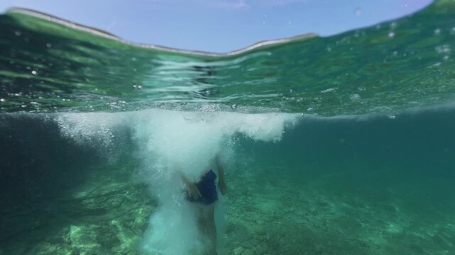 Split level view of a boy jumping into the sea water with splash
