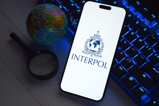 The smartphone with Interpol logo displayed on screen. International Criminal Police Organization or Interpol.
