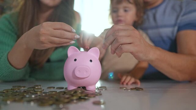 Family saving money piggybank for mortgage. Parents teach child importance money management by adding coins. Family working together to save money for mortgage. Child learns value saving for mortgage.