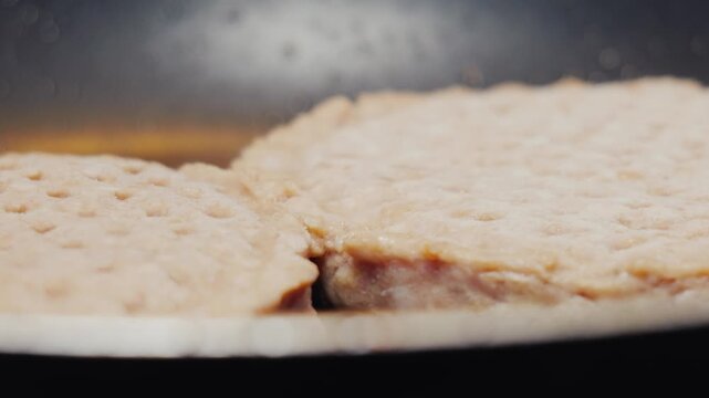 Frozen turkey sausage patties frying in hot skillet pan