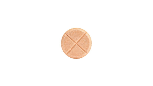Single round orange medicinal pill with a deep cross score mark for easy splitting captured in a macro studio shot presented isolated on transparent background