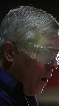Vertical video: Reacting to lens flare, mature man speaking in lab, wearing goggles and dark shirt