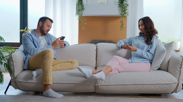 Caucasian using mobile phones ignoring separated woman looking at man with sad suffering relationship crisis bored at home couch family scrolling social media addict problem overuse smartphones