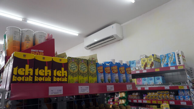 Purwokerto, Indonesia - 19 June 2026: Store shelf stocked with boxed drinks and packaged goods beneath an air conditioner unit.