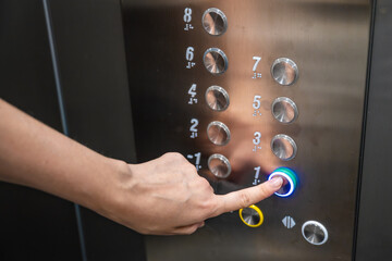 Person pressing the first floor button inside a modern residential elevator. Everyday elevator use supports convenient access and efficient movement between building levels © dtatiana