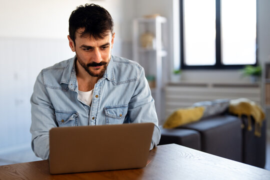 Home office. One smiling man using laptop. Work, freelance, social media, technology concept.
