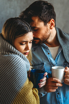 Sick man and woman wrapped in blankets suffering from cold or flu