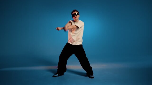 Hip hop dancer performs dynamic freestyle move against blue studio background