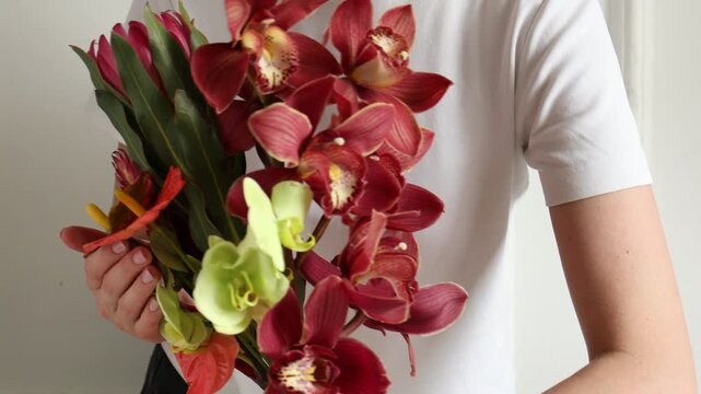 Woman holding bouquet of tropical flowers indoors, closeup