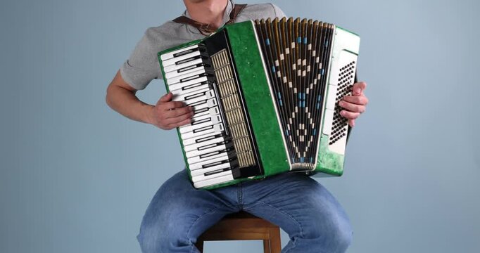 Man playing piano accordion on light background, closeup