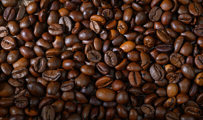 Obraz premium Rich and aromatic roasted coffee beans scattered on a wooden surface showcasing their deep, earthy hues