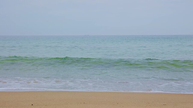 きれいな砂浜に打ち寄せる半透明のエメラルドグリーンの波と白い泡のクローズアップ