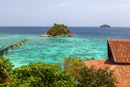 Ko Usen Islet view from Ko Lipe. Turquoise waters surround lush green islands. Roof partially visible in foreground.