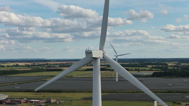 Wind Turbines Spinning in Vast Green Fields Under a Blue Sky