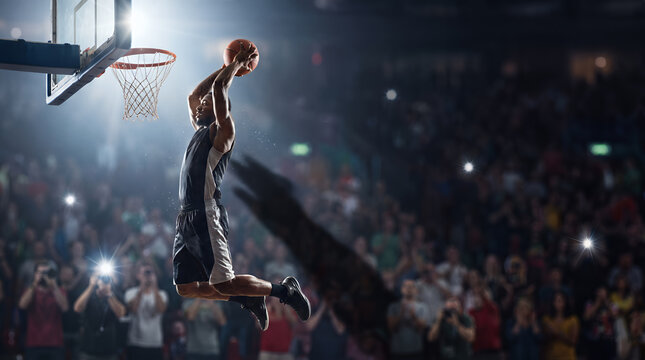 Professional basketball player jumping high for a slam dunk in a crowded arena