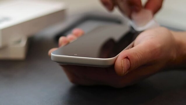 Male hand cleans smartphone screen with cloth while holding device