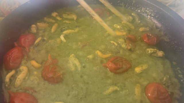 a delicious sauce cooking with basil pesto, mussels, and cherry tomatoes to toss the pasta in the pan