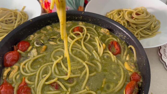 a delicious sauce cooking with basil pesto, mussels, and cherry tomatoes to toss the pasta in the pan