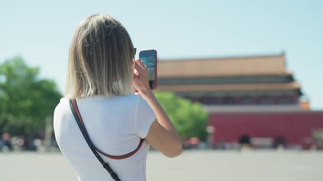Woman tourist taking mobile picture of Palace Museum, UNESCO World Heritage Site . Travel in China, visit Asia and explore unique culture, architecture and history of Chinese states and Imperial China
