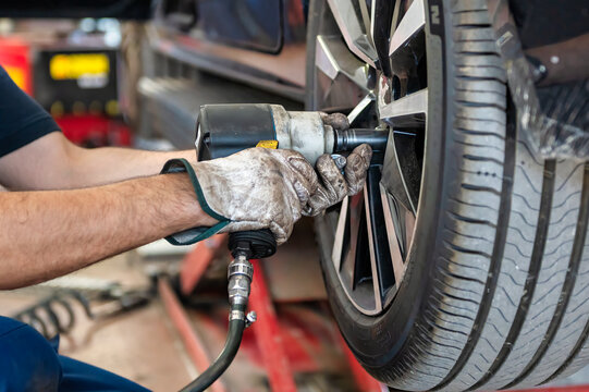 Professional mechanic using a tire changing machine to mount or remove a tire from an alloy wheel in an automotive workshop
