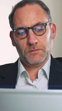 Businessman with glasses working on mobile device - vertical video