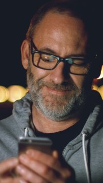 Smart handsome adult man use his smart phone outside in the city. Using smartphone technology makes him smiling happy wearing urban outfit. vertical video