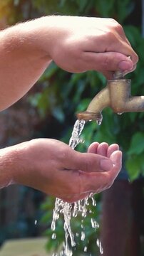 super slow motion shot of exterior tap water dripping and splash on a hot summer day - vertical video