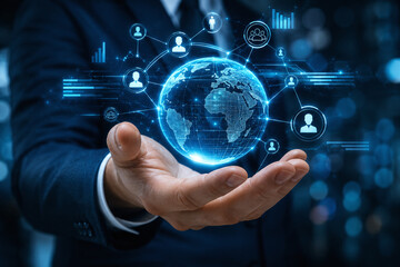 Fototapeta premium Businessman holding virtual digital globe with human resource icons, representing global business networking, recruitment, and digital connection technology on dark blue background. 