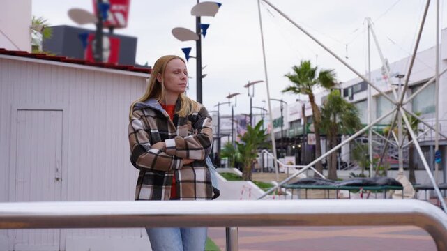 Young woman in jeans and jacket standing outdoors while waiting for someone. Concept of anticipation, meeting, urban lifestyle, everyday life, patience, and social connection.