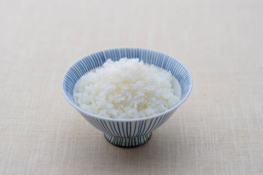 A bowl of steaming white Japanese rice served in a traditional blue patterned ceramic bowl