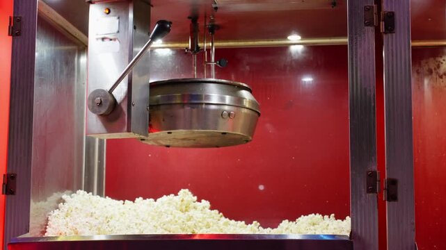 Commercial popcorn machine heating up with steam rising from hot kettle before popcorn begins popping. Concept of food preparation, snack production, cinema concession, professional kitchen equipment