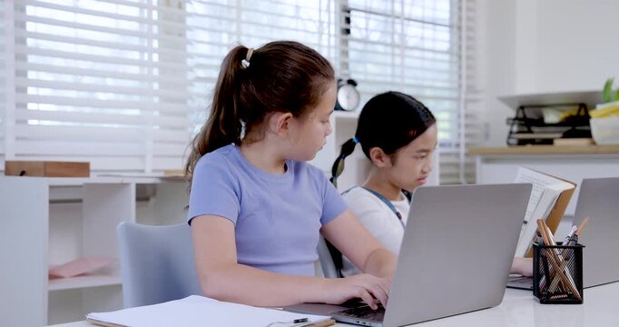 Asian preteen girl smiling while using laptop beside caucasian girl in classroom digital learning project teamwork illustrating education childhood collaboration productivity communication study